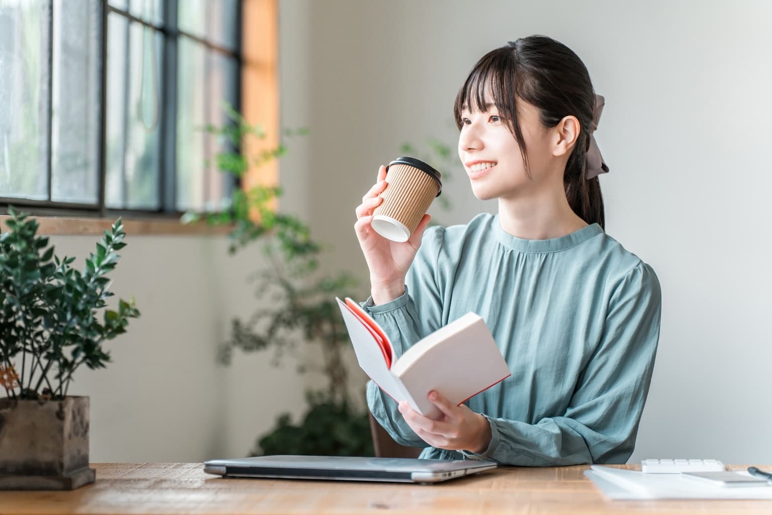 本を読みながらコーヒーを手に、落ち着いた空間で学ぶ女性のイメージ｜アメリカ留学のMIYACO