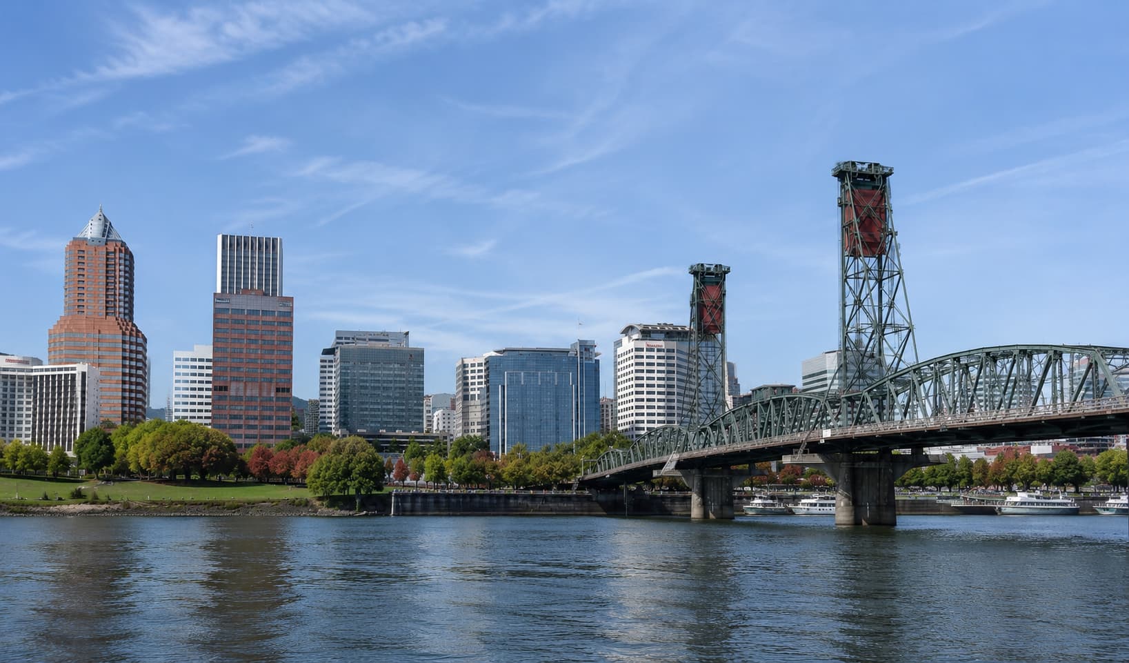 Portland のダウンタウンと鋼鉄橋を望むウィラメット川沿いの晴天風景